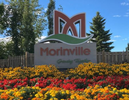 Morinville sign with colorful flowers and trees